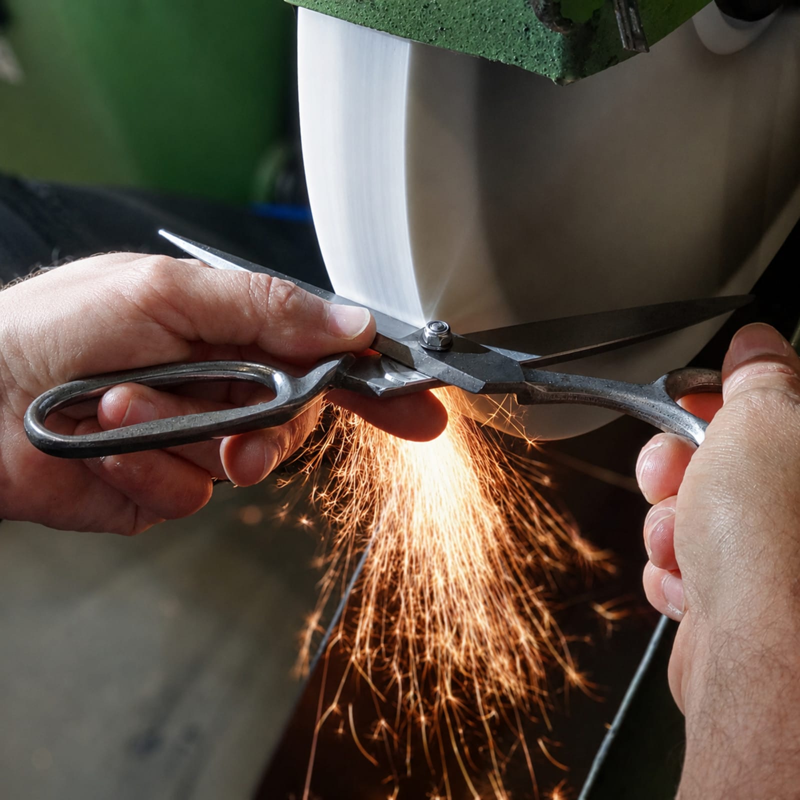 A person sharpening a knife on a grinding wheel. The hands are holding the knife close to the spinning wheel. The setting appears to be a workshop.