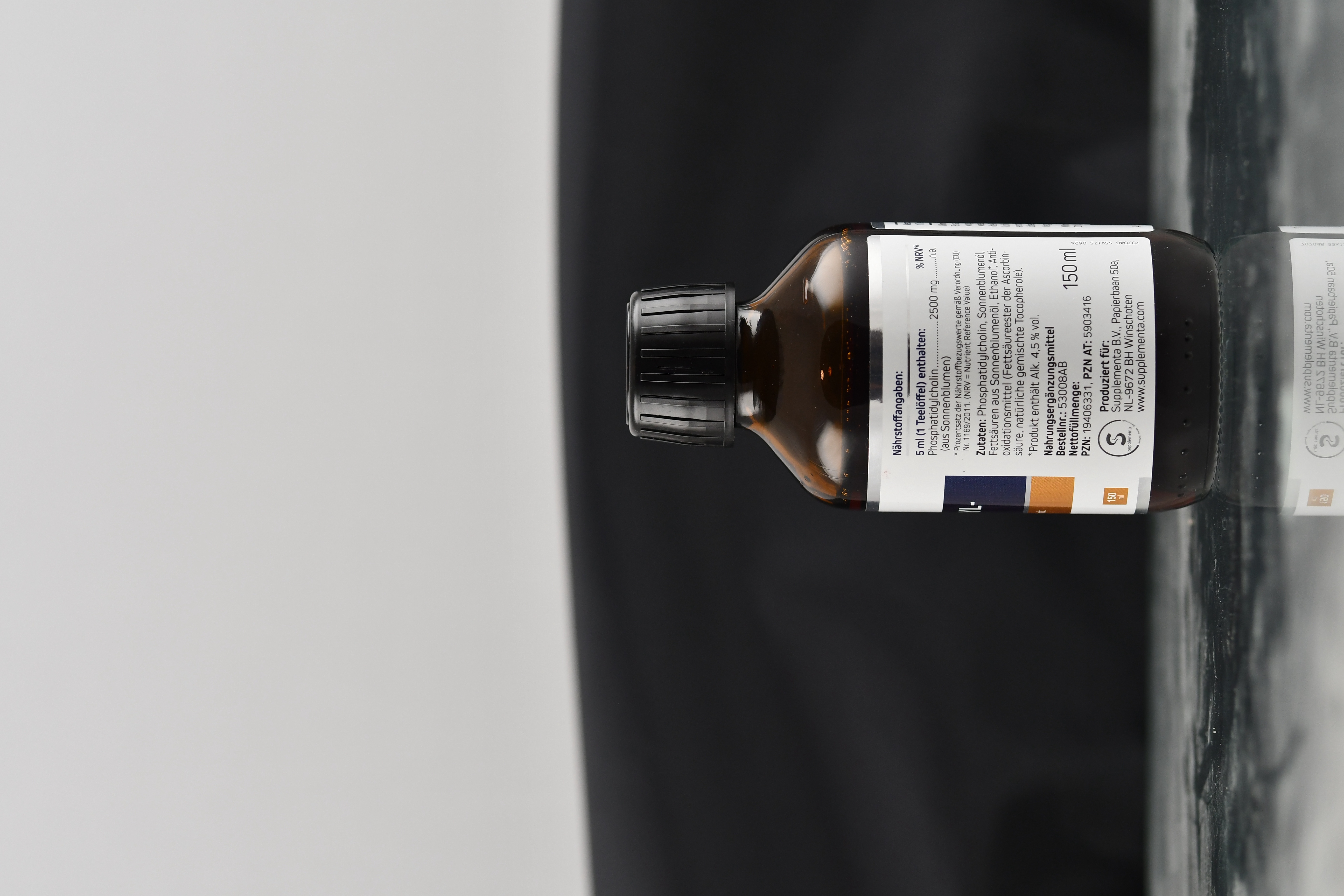 Produktfoto: Eine braune Glasflasche mit schwarzem Schraubverschluss, etikettiert mit 'American Biologics Phosphatidyl-Cholin'. Das Etikett zeigt Informationen über das Nahrungsergänzungsmittel, einschließlich 'vegan' und 'non-GMO'. Die Flasche enthält 150 ml.