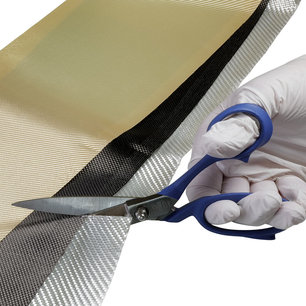 A gloved hand is using blue-handled scissors to cut through a layered material of different colors and textures.