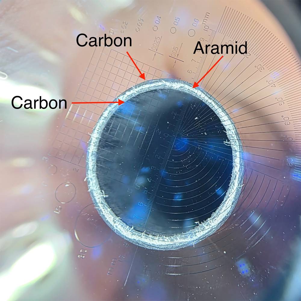 The image shows a close-up of the construction of a aramid-carbon tube. Outer-layer of Carbon, intermediate layer of aramid and an inner layer of carbon.