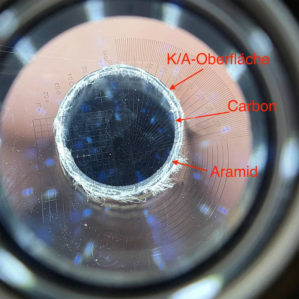 The image shows a close-up of the construction of an aramid-carbon tube. Outer layer made of hybrid carbon-aramid fabric, an intermediate layer made of aramid fabric and an inner layer made of carbon.