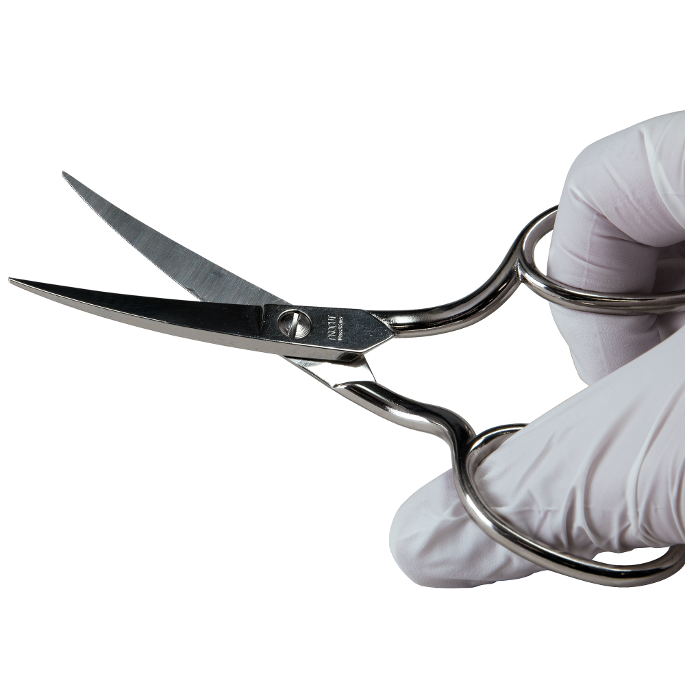 Eine Hand in einem weißen Handschuh hält eine kleine silberne Schere.