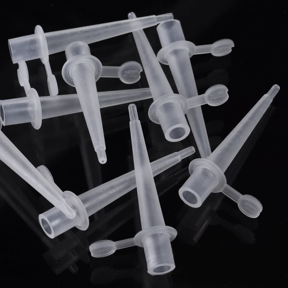 Several transparent plastic conical tubes with attached flat caps are scattered on a reflective black surface.