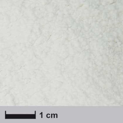 Nahaufnahme einer weißen, pulverartigen Substanz mit einer Skala von 1 cm.