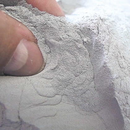 Nahaufnahme einer Hand, die graues Pulver hält.