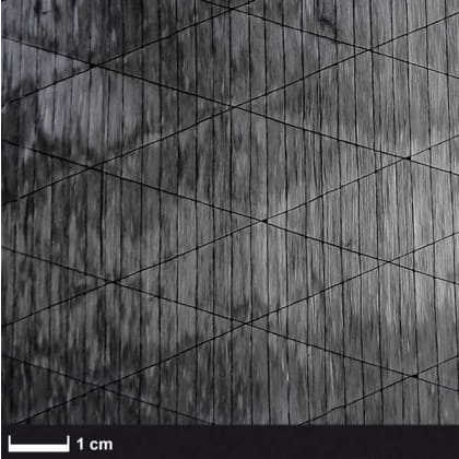 Das Bild zeigt eine Oberfläche mit einem regelmäßigen Rautenmuster. Die Struktur wirkt texturiert und hat eine graue Farbgebung. Unten links ist eine Maßstabsleiste von 1 cm zu sehen.