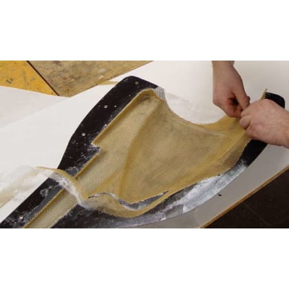 Zwei Hände arbeiten an einem Stück Stoff oder Material, das über eine Form gespannt wird. Es handelt sich um ein handwerkliches Projekt.