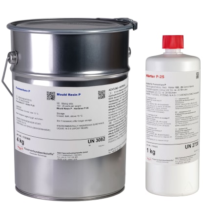 Zwei glänzende, schwarze Teile auf Holzgestellen in einer Werkstatt mit Regalen und Materialien im Hintergrund.